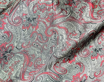 May include: A close-up of a fabric with a paisley pattern in shades of red, black, and white.