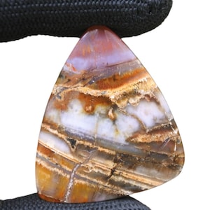 May include: A triangular shaped piece of agate with brown, white, and orange banding. The agate has a natural, polished finish.