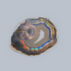 May include: A slice of agate featuring a range of colours, including brown, grey, blue, and red. The agate has an iridescent sheen and a hole in the centre.