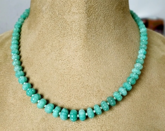 May include: A light green gemstone necklace with round beads. The necklace is displayed on a brown velvet mannequin.