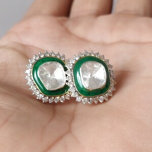 Puede incluir: Un par de pendientes de plata con esmalte verde y una gran piedra preciosa facetada transparente en el centro de cada pendiente.