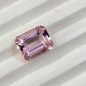 May include: A light pink gemstone with a rectangular emerald cut.