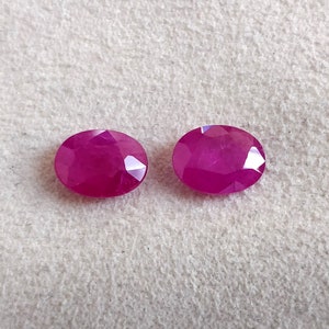 Puede incluir: Dos piedras preciosas ovaladas de color rosa intenso con corte facetado.