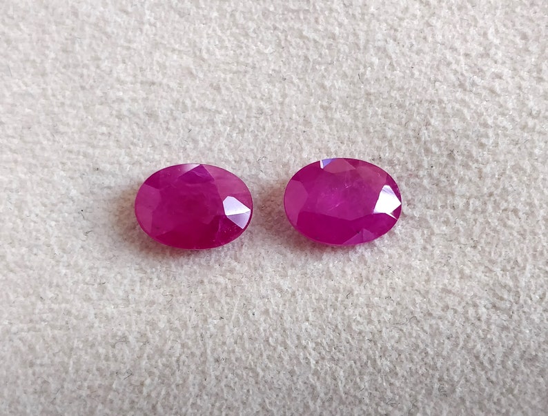 Puede incluir: Dos piedras preciosas ovaladas de color rosa intenso con corte facetado.