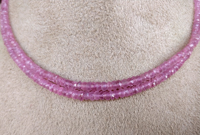 Pode incluir: Um colar de duas voltas feito de contas de pedras preciosas cor-de-rosa. As contas s&atilde;o facetadas e t&ecirc;m uma cor rosa claro.