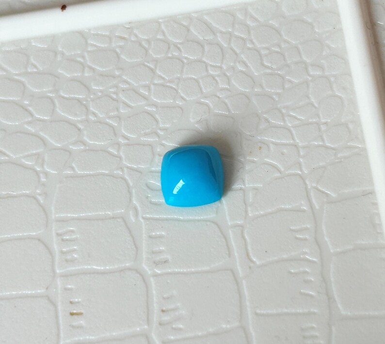 May include: A square shaped turquoise gemstone with a smooth, polished surface.