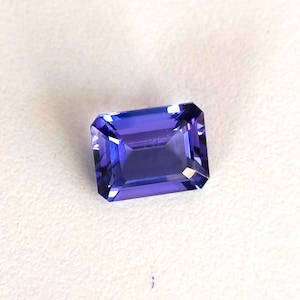 K&ouml;nnte beinhalten: Ein tiefblauer, rechteckiger, facettierter Edelstein mit einem leichten violetten Farbton.