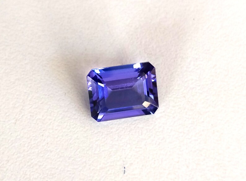 K&ouml;nnte beinhalten: Ein tiefblauer, rechteckiger, facettierter Edelstein mit einem leichten violetten Farbton.