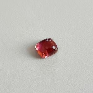 Pode incluir: Uma gema vermelha, rosa e verde com corte almofada.