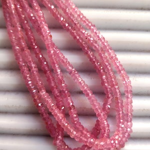 Pode incluir: Um fio de contas de pedras preciosas cor-de-rosa, provavelmente quartzo rosa, com acabamento facetado. As contas s&atilde;o enfiadas em um fio transparente e est&atilde;o dispostas em um padr&atilde;o solto e fluido.