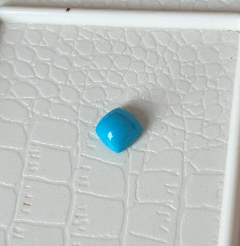 May include: A bright turquoise gemstone with a square shape and a smooth, polished surface.