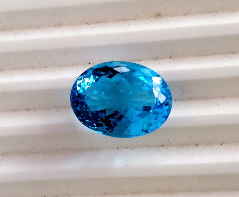 May include: A bright blue oval-shaped gemstone with a faceted cut.