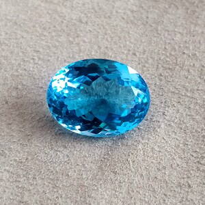 May include: A large, oval-shaped, blue topaz gemstone with a faceted cut.