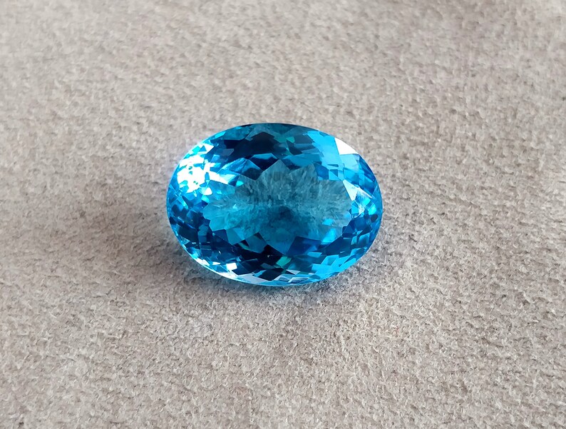 May include: A large, oval-shaped, blue topaz gemstone with a faceted cut.