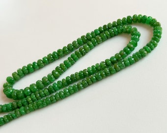May include: A strand of green emerald beads, each bead is faceted and has a rounded shape.