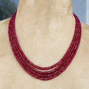 May include: A multi-strand necklace made of deep red ruby beads. The necklace is made of four strands of beads, each strand is about 18 inches long.