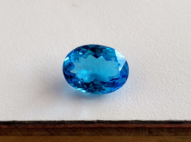 May include: A bright blue oval-shaped gemstone with a faceted cut.