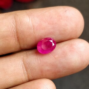 Puede incluir: Una gema ovalada de color rosa vibrante con facetas.