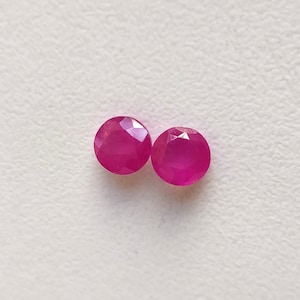 May include: Two round, faceted, pink gemstones.