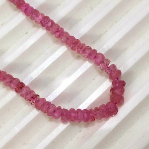 Pode incluir: Um fio de contas de pedras preciosas cor-de-rosa. As contas s&atilde;o facetadas e t&ecirc;m um formato ligeiramente irregular. As contas s&atilde;o enfiadas num fio transparente.