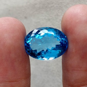 May include: A large, oval-shaped, blue topaz gemstone with a faceted cut.