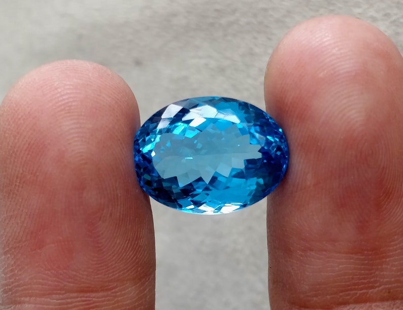 May include: A large, oval-shaped, blue topaz gemstone with a faceted cut.
