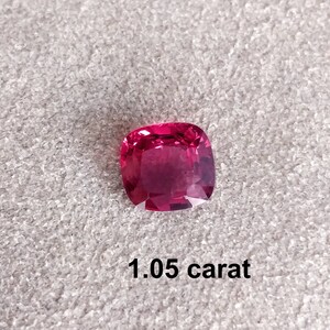 Pode incluir: Uma gema rosa vibrante, cortada em forma quadrada, com acabamento polido. A gema tem 1,05 quilates.
