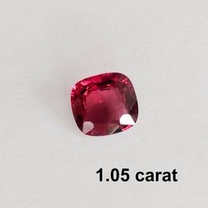 Pode incluir: Uma gema vermelha escura com corte almofada, pesando 1,05 quilates.
