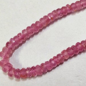 Pode incluir: Um fio de contas de pedras preciosas cor-de-rosa. As contas s&atilde;o facetadas e t&ecirc;m uma forma ligeiramente irregular.