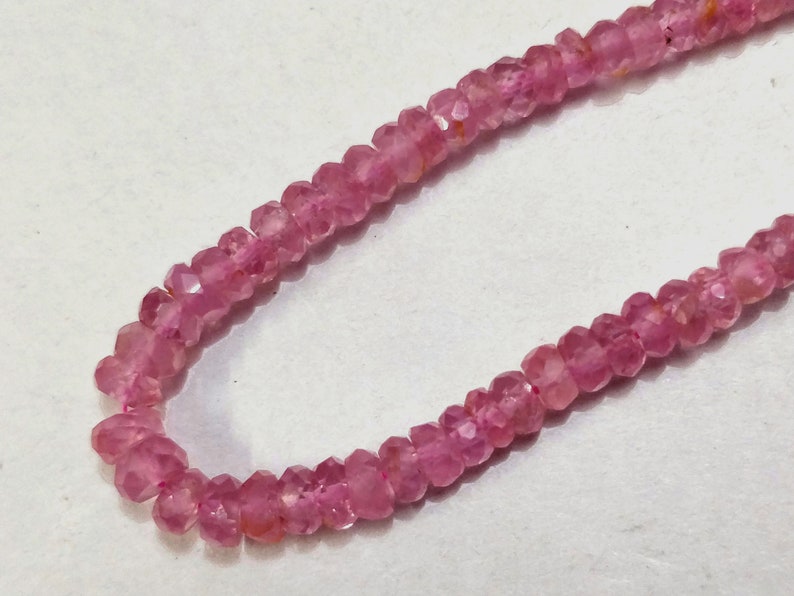 Pode incluir: Um fio de contas de pedras preciosas cor-de-rosa. As contas s&atilde;o facetadas e t&ecirc;m uma forma ligeiramente irregular.