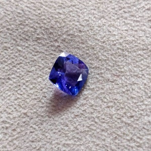 Puede incluir: Una piedra preciosa de forma cuadrada, de color azul oscuro, con un corte cojín.