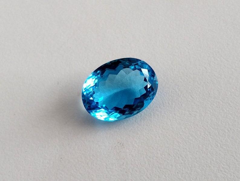 May include: A bright blue oval-shaped gemstone with a faceted cut.