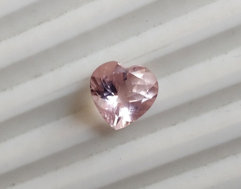 Op de afbeelding: Een roze edelsteen in de vorm van een hart met facetten.