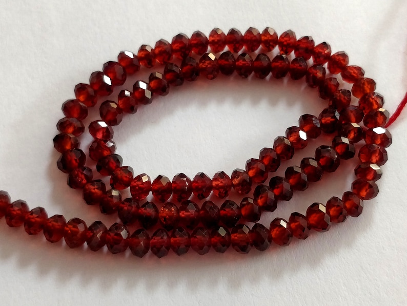 May include: A strand of deep red faceted garnet beads. The beads are strung on a clear thread and are approximately 4mm in diameter.