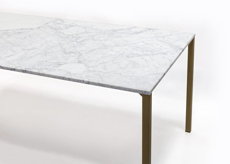 Puede incluir: Una mesa de comedor rectangular con una tapa de m&aacute;rmol blanco y patas de metal dorado.