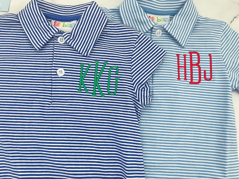 May include: Two short-sleeved polo shirts featuring white and blue horizontal stripes. The left shirt is dark blue with green embroidered KKG initials. The right shirt is light blue with red embroidered HBJ initials. Both feature white buttons and Tell Bean labels.