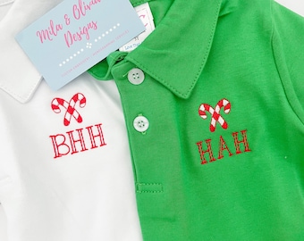 May include: Two white and green polo shirts with red candy cane embroidery and personalized monograms. The white shirt has the monogram "BHH" and the green shirt has the monogram "HAH".