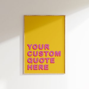 Op de afbeelding: Een gele geframed poster met de tekst "YOUR CUSTOM QUOTE HERE" in roze letters.
