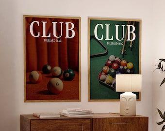 Może przedstawiać: Dwa oprawione plakaty ze słowem "CLUB" i "BILLIARD MAG" w białym tekście. Jeden plakat przedstawia kule bilardowe na czerwonej powierzchni, drugi na zielonej. Lampa i drewniana szafka znajdują się na pierwszym planie.