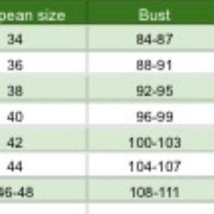 Op de afbeelding: Een maattabel met internationale en Europese maten, borst-, taille- en heupmaten in centimeters. Maten vari&euml;ren van XS tot XXXL, met bijbehorende afmetingen. De tabel heeft een lichtgroene achtergrond.