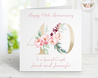 May include: A white card with gold lettering and pink flowers. The card says "Happy 40th Anniversary" and "To a Special Couple Jacob and Jennifer".