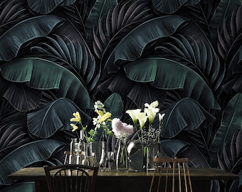 May include: A dark wood dining table with four chairs, set against a backdrop of a tropical leaf wallpaper. The table is decorated with a vase of white and yellow flowers.