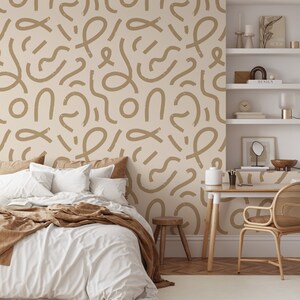 Puede incluir: Un interior de dormitorio con una cama blanca con ropa de cama marrón y un papel tapiz con estampado marrón. El papel tapiz presenta un patrón repetitivo de líneas y formas marrones sobre un fondo beige claro. Hay un taburete de madera y un escritorio con una silla en la habitación.