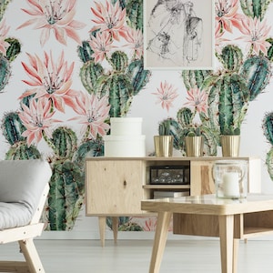 May include: A living room interior with a light grey sofa and a wooden coffee table. The wall is covered in a wallpaper with a repeating pattern of pink cactus flowers and green cacti.