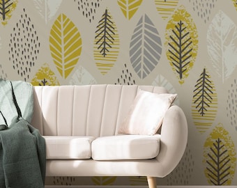 Puede incluir: Un sofá color crema con una manta verde y un cojín blanco se encuentra frente a una pared con un estampado de hojas. El papel pintado presenta diseños de hojas amarillas, grises y blancas sobre un fondo beige, creando un tema inspirado en la naturaleza.