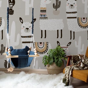 May include: A nursery room with a gray wall featuring a llama pattern. A wooden baby swing with a blue seat hangs in front of the wall. A potted plant sits on the floor next to a brown chair with a green and white throw blanket.