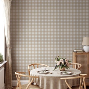 May include: A dining room with a beige and white gingham wallpaper. A table with a beige tablecloth is set with four chairs and a bouquet of flowers in a gold vase.