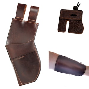 May include: A set of archery accessories in brown leather. Includes a quiver with belt loops, a finger tab, and an arm guard. The quiver has the text "SHOTPROOF" stitched on it.