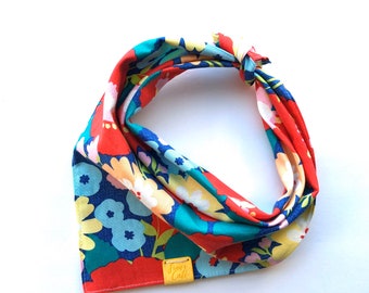 May include: A red, blue and yellow floral print bandana with a yellow tag that says "Finn's Cafe".