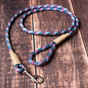 May include: A blue, pink, and white rope dog leash with a brown leather handle and a silver clip.
